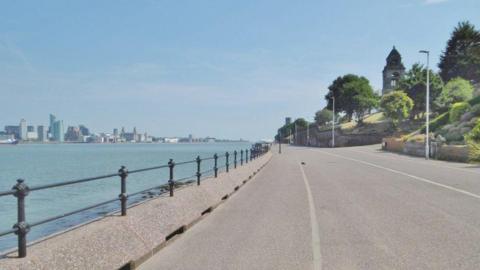 The riverfront path at Seacombe overlooks the water on a sunny day with milky blue skies.