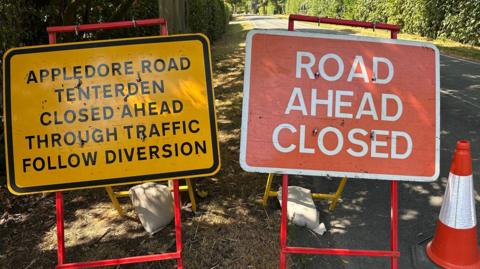 One road sign that reads "road ahead closed" and another reads Appledore Road Tenterden closed ahead through traffic follow diversion.