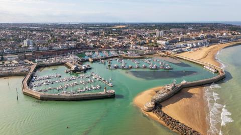 An aerial image of a harbour on the coast of a large town
