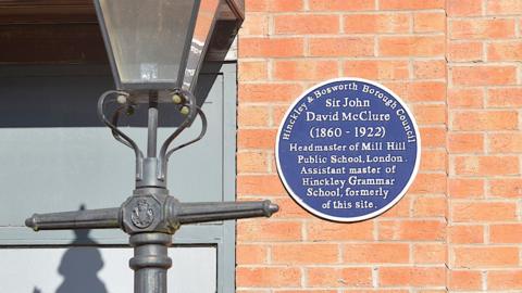 A blue plaque on a wall next to a lamppost