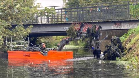 Workers recover shopping trolleys from the water