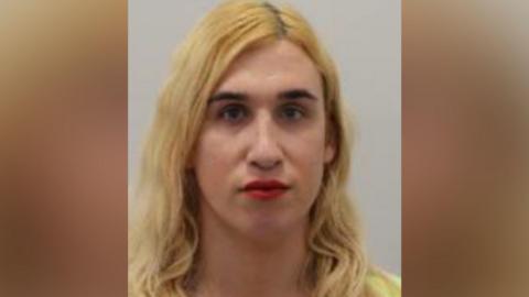 A police mugshot of Vivienne Taylor, who has long blonde hair, a yellow top and red lipstick