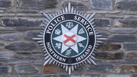 Police crest on a brick walled building - the crest says Police Service Northern Ireland with emblems 