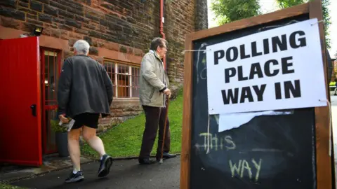A man passes a woman as he walks into a polling station