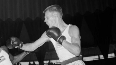 A boxer in a white vest throws a punch