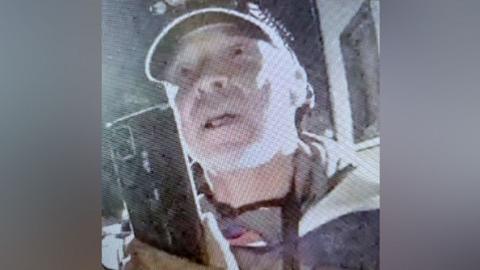 A grainy image of Gavin Turpie, a man with a baseball cap on.