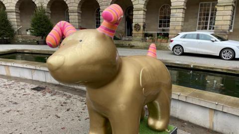 A sculpture of a golden snow dog stood outside the Buxton Crescent