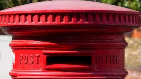 The top of a red post box 