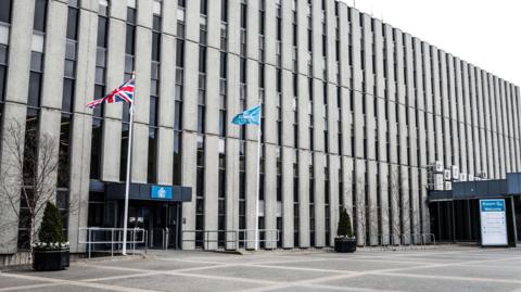 The outside of the Darlington council building. It is a large concrete building with two flag poles outside.