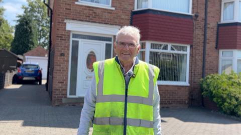 Man wearing a hi-vis jacket in front of a terrace house