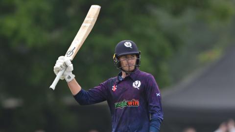 Brandon McMullen raises his bat for reaching 50 against Australia in 2024