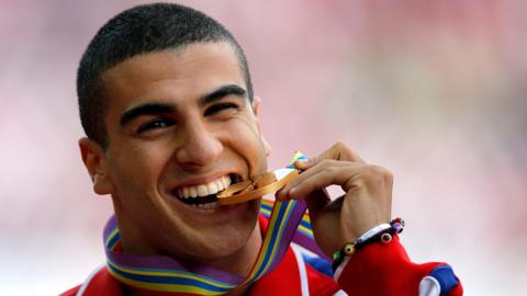 Adam Gemili biting a gold medal.