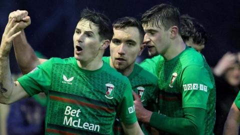 Ciaron Coll and David Fisher celebrate with goalscorer Joe Thomson