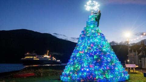Ullapool's Gordon Wink places the "star" on to top of the village's creel tree. The star is the outline of crab decorated with white lights.