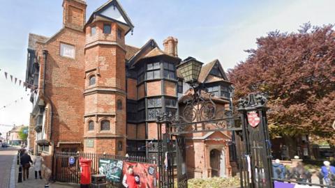 A Google Maps image of Eastgate House in Rochester, an historic tudor style building with traditional red brick, black beams and turrets