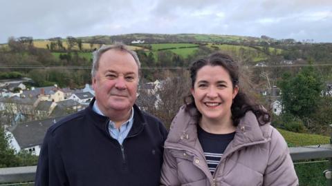 Andrew McAlister and his daughter Maeve standing together with a view of Cushendall village behind them