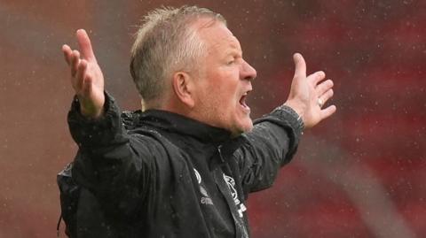 Chris Wilder has his arms stretched out in protest