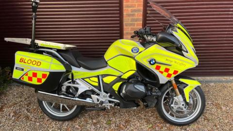 A luminous yellow motorbike with the word "blood" written on the back.