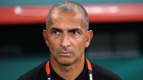 Close up of Sabri Lamouchi standing in the dugout looking focused