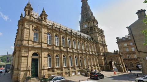 Halifax Town Hall - a grand, light brown-coloured Georgian building pictured in the sunshine.