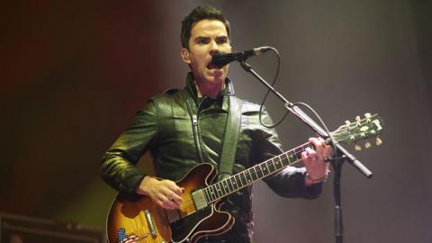  Kelly Jones of the Stereophonics performs during Victorious Festival at Southsea Common on August 26, 2022 in Portsmouth, England. He is wearing a green leather jacket, is playing an electric guitar and it singing into a micrphone