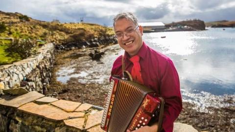 Fireannach na shuidhe ri taobh na mara agus maileòidean aige.
