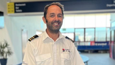 Robin Fitzgerald is wearing a Ports of Jersey uniform and is standing in the refurbished ferry departure terminal.