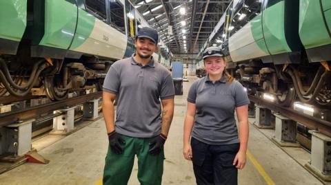 From left: Second year engineering apprentices Elias Pablo and Katie Short stand in front of two green Southern trains