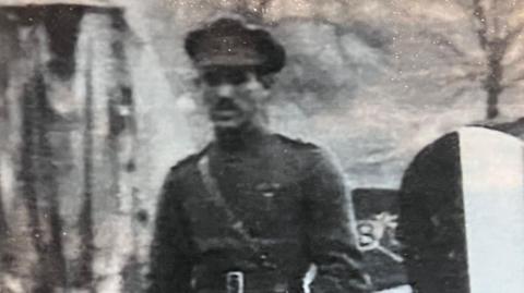 A fuzzy picture of a World War One airman in front of a plane.