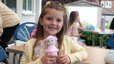Girl holding a knitted doll.