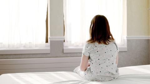 An anonymous girl sitting on a hospital bed