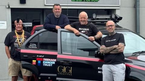 Derek Howarth, Paul Cobb, Steve Silver, and Daniel Nowell posing with their car which they will take to Europe, with the sponsors on the doors.