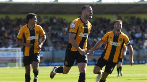 James Gibbons of Cambridge runs with his right fist clenched as two team-mates run either side of him