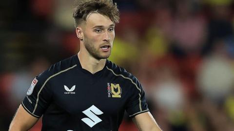 Sam Sherring with the ball between his feet during a match for MK Dons last season