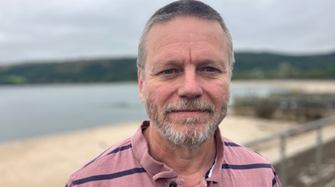 Gavin Angus wearing a pink and blue striped polo shirt.