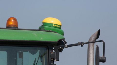 A yellow and green small round dome-like equipment, placed on top of a green tractor.