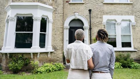 Rear view of a couple looking at a restored Victorian house