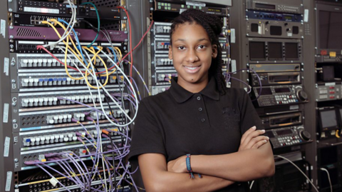 Woman in front of technical equipment with lots of cables 