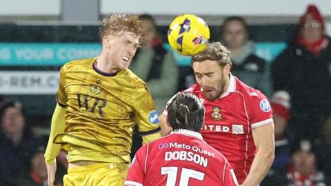 George Pratt wins a header against Wrexham