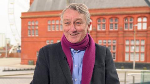 Anthony Slaughter, who has grey hair, wearing a purple scarf
