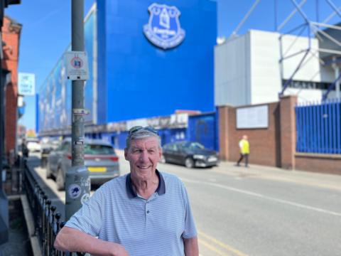 Ray Parr is standing in front of 9 Goodison Road and smiling directly in the camera. Behind him in the background is Goodison Park.