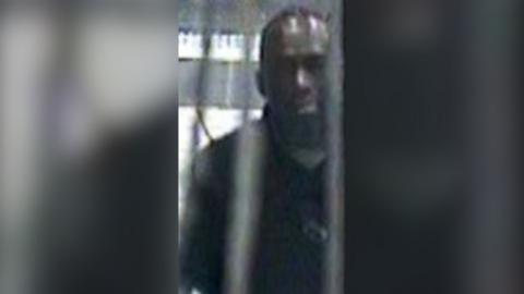 A grainy CCTV image of a man in a Tube station.