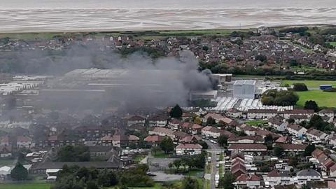 Drone image of huge plumes of black smoke billowing from the former Typhoo Tea factory in Moreton.