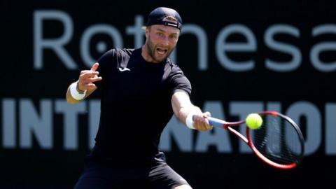 Liam Broady hits a tennis ball with his racquet