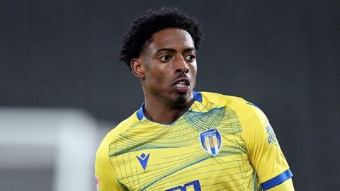 Kyreece Lisbie looking down to his left head and shoulders shot wearing Colchester United's home yellow and blue kit 