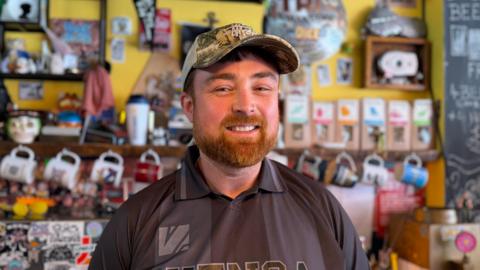 A man with a ginger beard wearing a black shirt and camouflage hat.