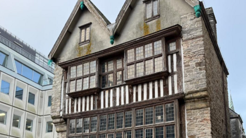 A picture of the outside of the house. It features large bricks with panelled windows and wooden panels. 
