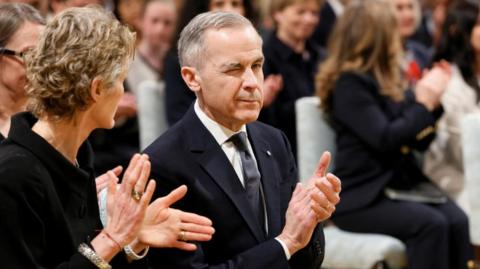 Mark Carney winks as he applauds during a ceremony to swear him in as Canada's prime minister