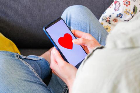 a child looks at an image of an emoji heart on the screen of their smartphone