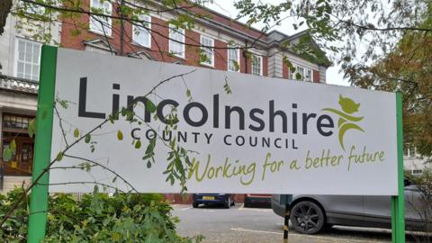 A sign outside a public building which says "Lincolnshire County Council, working for a better future".